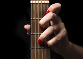 female hand grips the guitar strings