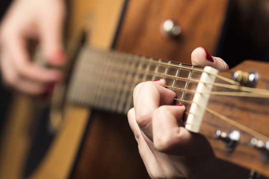 Young woman clamped with fingers guitar strings