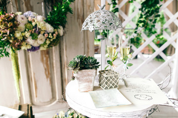 Little flowerpot with greenery, lamp and champagne flutes stand
