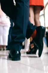 Man in leather shoes and red socks stands before woman in red dr