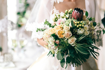 Gorgeous bouquet of roses and greenery held by elegant bride