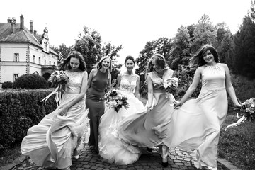 Charming bride and bridesmaids wave their dresses while they wal