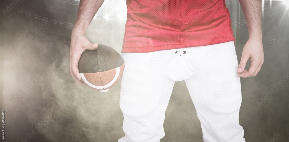 Wall mural Composite image of american football player holding a ball