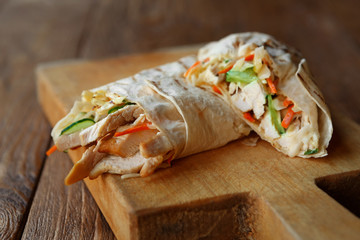 Burrito with pork meat and vegetables at wood desk