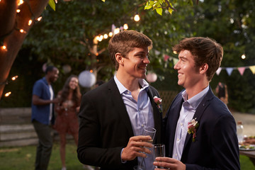 Gay Couple Celebrating Wedding With Party In Backyard