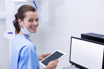 Smiling dental assistant holding digital tablet