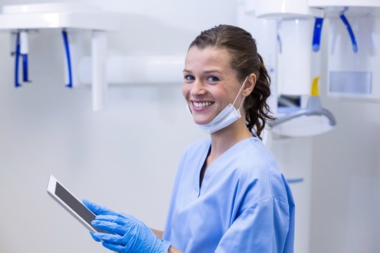 Smiling dental assistant using digital tablet - Powered by Adobe