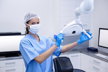 Smiling dental assistant adjusting light