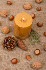 Walnuts, hazelnuts, cone, candle, fir branch on sackcloth fabric