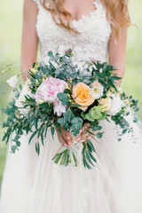 Beautiful wedding bouquet in hands of the blonde bride.