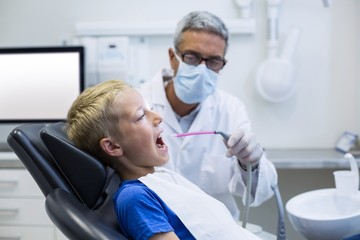 Dentist examining a young patient with tools 