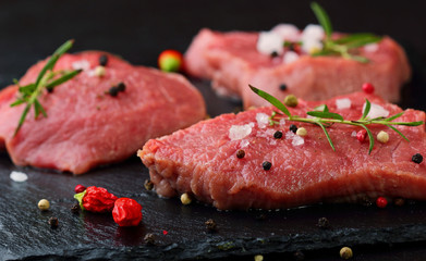 Fresh Raw Beef steak Mignon, with salt, peppercorns, rosemary, pepepr chili.On dark table.Copy space.Selective focus