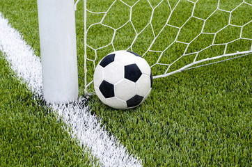The soccer football with the net on the artificial green grass soccer field