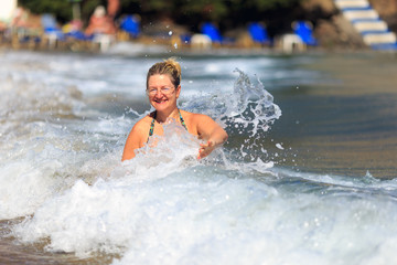 Woman in a bathing suit splashing in the waves. Greece.