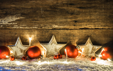 Weihnachten Hintergrund Dekoration mit Holz Sterne weiß, Kugeln rot und Lichterkette im Schnee 