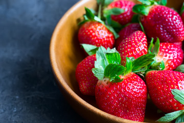 Juicy ripe strawberries in a wooden bowl closeup, selective focu