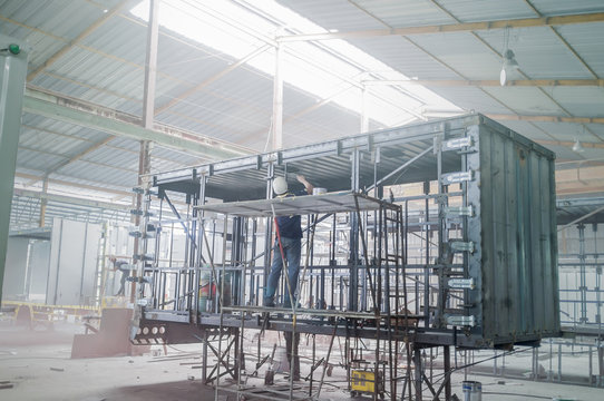 Industry worker with welding steel to build container structure.