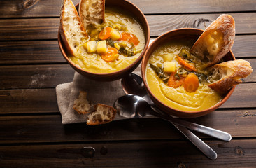 two bowls of Hot Soup on a wooden table with fresh crispy bread