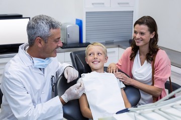 Obraz premium Dentist interacting with mother and son while dental examination