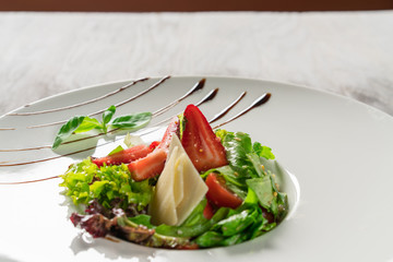 Salad greens, cheese and strawberries with balsamic sauce.
