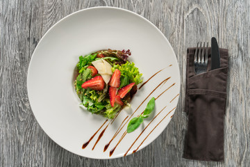 Salad greens, cheese and strawberries with balsamic sauce.