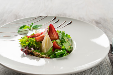 Salad greens, cheese and strawberries with balsamic sauce.