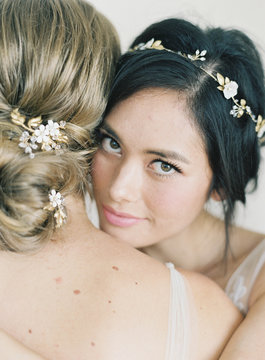 Two women wearing bridal wear, hugging