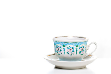 Ornamental tea cup with saucer on white background. Porcelain dishes, kitchenware. Decorative background.