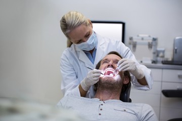 Obraz na płótnie Canvas Dentist examining a patient with tools
