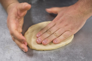 Close up view of a baker man hands kneading a dough.