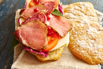 sandwich with ham,cheese and fresh vegetables on rustic dark background and lining napkin. Cooking, eating concept.