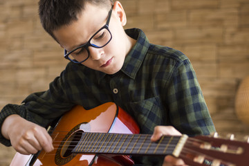Boy With Glasses Playing Acoustic Guitar in Living Room - 129581520