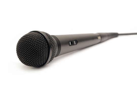 Black vocal microphone with on button on body and wire isolated on white background side view closeup