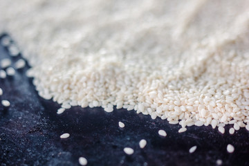 White sesame seeds over the black metal tray.