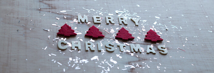 Wooden white "Merry christmas" with christmas trees and sparkly decor on wooden background.