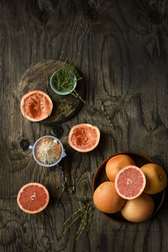 Whole and sliced grapefruits, with fruit squeezer and fresh thyme