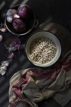 Bowl of black eyed peas on table with red onions and garlic, overhead view