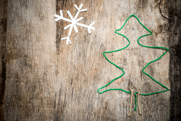 Christmas tree shape made of green wool and decorative snowflake on rustic wooden background