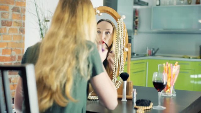 Girl looking at the mirror and putting mascara on her lashes
