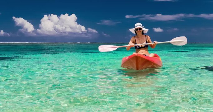 Young caucasian woman kayaking at tropical sea on yellow kayak