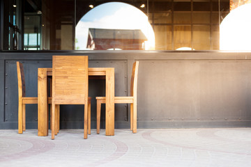 Outdoor wooden table and chair in front of restaurant. Soft focus and over lighting flares.