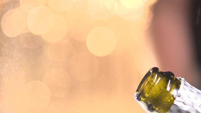 Opening champagne bottle closeup. Sparkling Wine over Holiday Bokeh Blinking Background. Slow motion 240 fps..