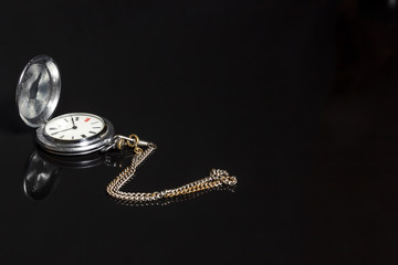 vintage silver pocket watch on black background with reflection