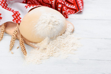 Ball of raw dough isolated on white wooden table with ears wheat. Copy space. Package. Top view. Russian or Ukrainian Style