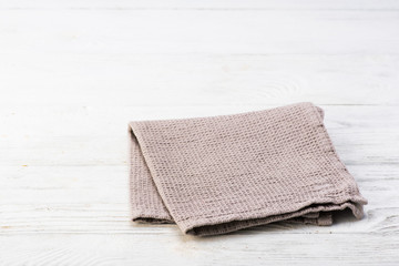 Fototapeta na wymiar Gray napkin isolated on white wooden table. Copy space. Brick wall background. Front view.