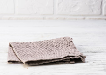 Gray napkin isolated on white wooden table. Copy space. Brick wall background. Front view.