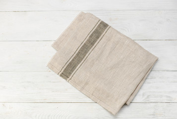 Gray napkin isolated on white wooden table. Copy space. Brick wall background. Front view.