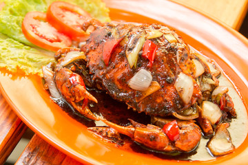 Crab cooked with black pepper sauce on plate with chili and onion