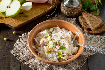 Fototapeta na wymiar Salad with sauerkraut, ham, apple and green peas. Snack on a fes