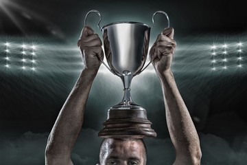 Composite image 3D of successful rugby player holding trophy